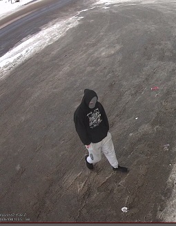Man wearing black hoodie with Harlie Davidson loge, grey ski mask and light colour jogging pants outside business