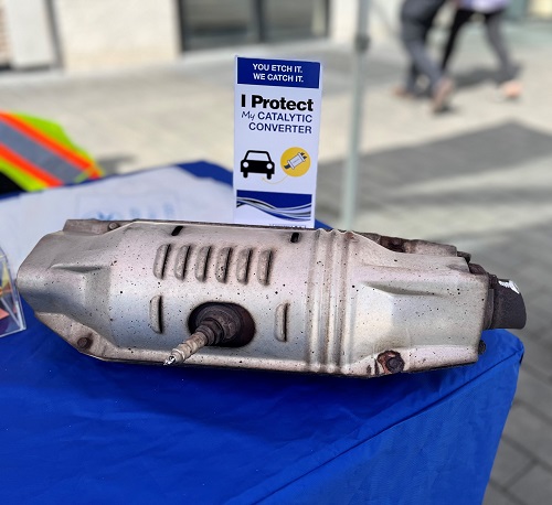 Photo of catalytic converter on table with sign that says "You Etch It. We Catch It. I protect my catalytic converter." 