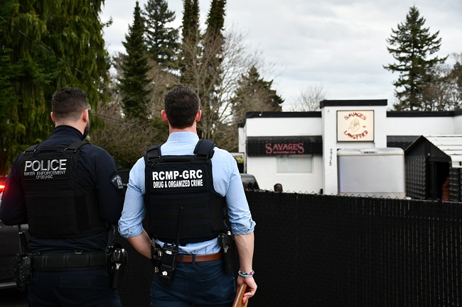Photo of West Shore RCMP and CFSEU-BC officer overlooking Savages Motor Cycle Club during search warrant. 