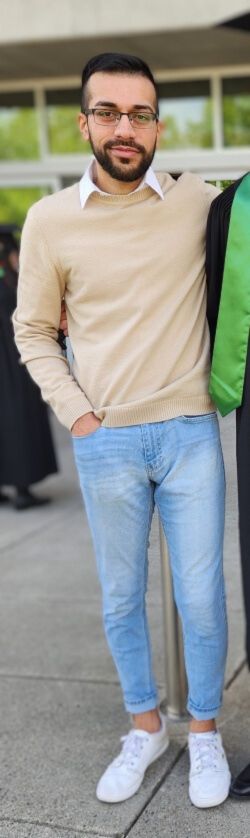 Photo de Jasdeep Parmar debout portant un pull crème avec un col de chemise blanc, un jean bleu et des chaussures blanches