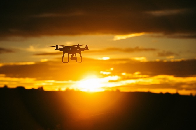 Picture of a drone flying in a sunset. 