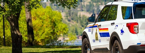 Une voiture de police garée près d’une plage au lac Okanagan