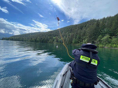 A member throws a tow line from a boat into Cultus Lake