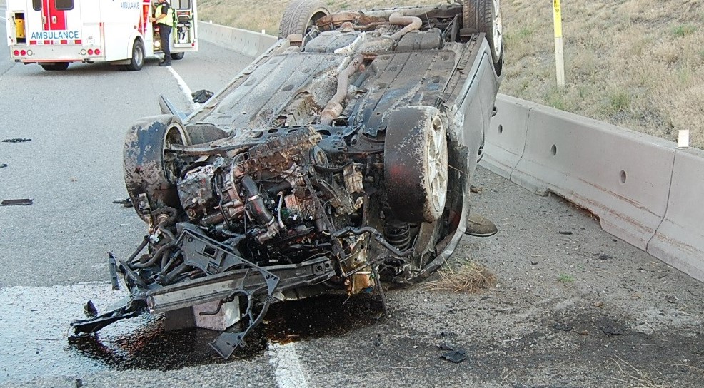 Photo d'une voiture accidentée à l'envers devant une ambulance de la Colombie-Britannique sur la route.