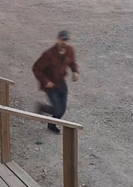 Description de la photo : Image d’un homme portant un pantalon foncé, une chemise rouge et une casquette qui court près de marches en bois. 