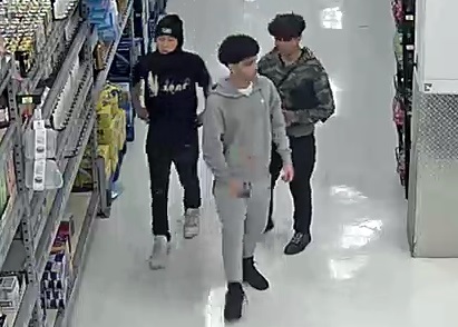 A frontal view of the three suspects walking in a group down an isle of the store
