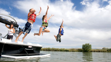 Kids wearing life jackets jumping off a boat