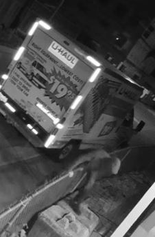 Photo captée à l’aide d’une vidéo de surveillance et montrant le suspect grimpant sur une clôture à mailles losangées, et le camion U-haul en arrière-plan.