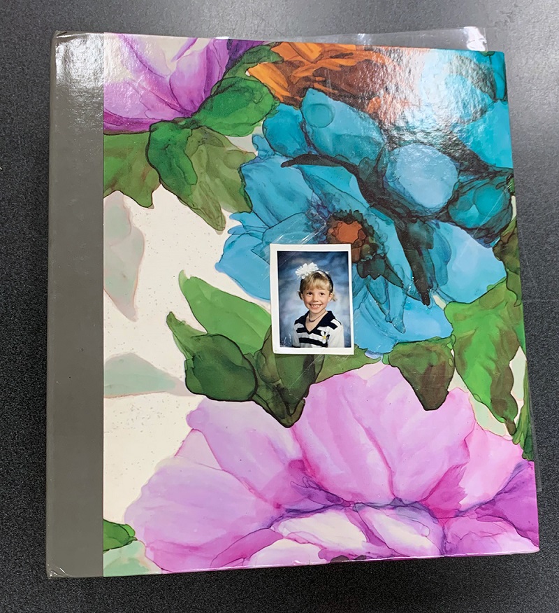 Album de photos avec des fleurs multicolores et une photo d’école d’une petite fille collée sur l’avant