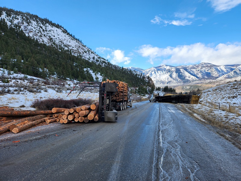Two rolled over semis with logs and  hay on ground
