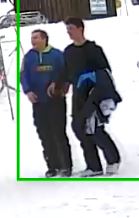 Les deux suspects marchent ensemble. L’un d’entre eux porte une veste bleue et l’autre est vêtu de noir et porte sa veste sur son bras.  