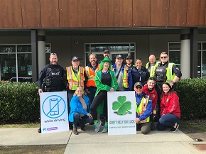 group picture of police officers a leprechaun mascot wearing a green outfit and volunteers.