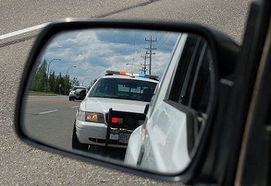 Image of a police vehicle seen through a side-view mirror