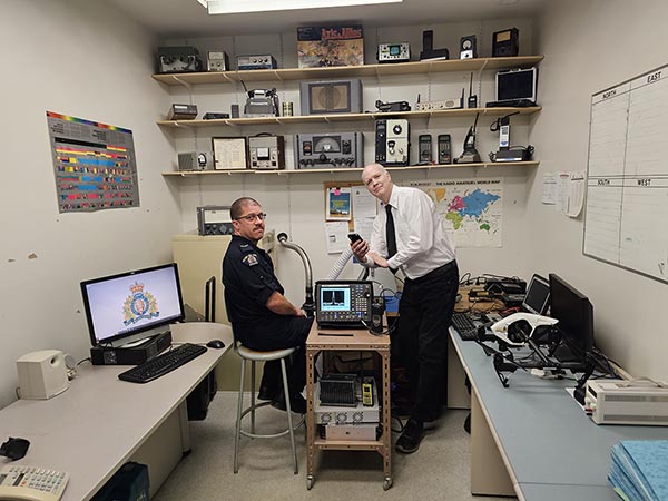 Photo de agent de la GRC et technicien en informatique dans une salle des radios moderne.