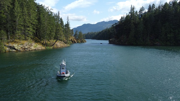 Cst Kyle Toole navigates the BC RCMP Zodiac boat in the blue waters of Harrison Lake at Sheers Island and Ten Mile Bay campsite.