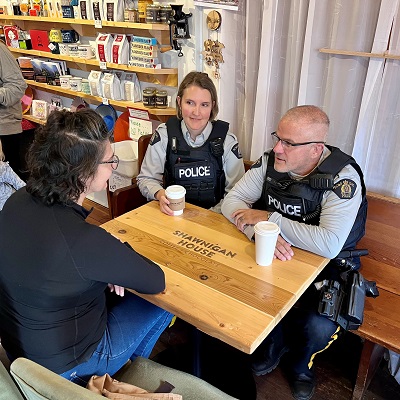 Two RCMP officers having a coffee with a member of the public